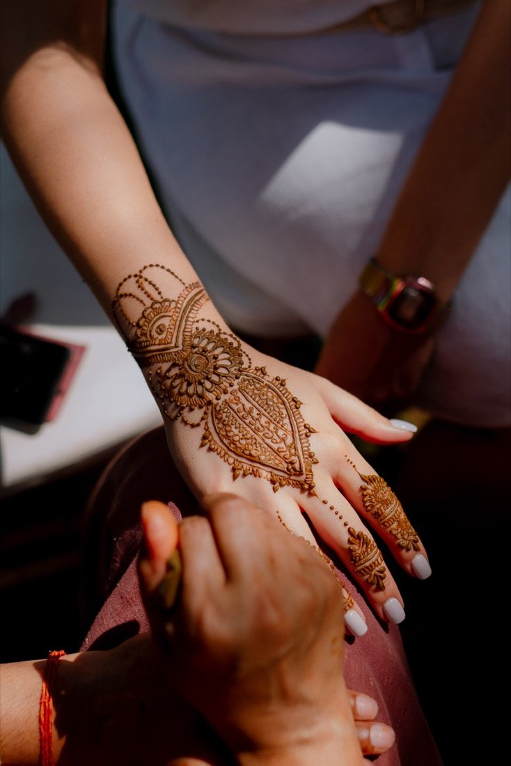 A bride's hennaed hand resting in the groom's