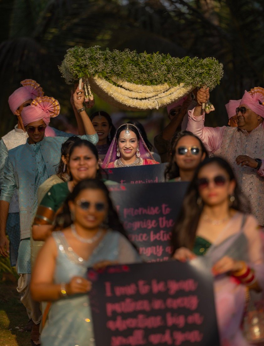 A bride walking beneath a canopy of flowers held by her family