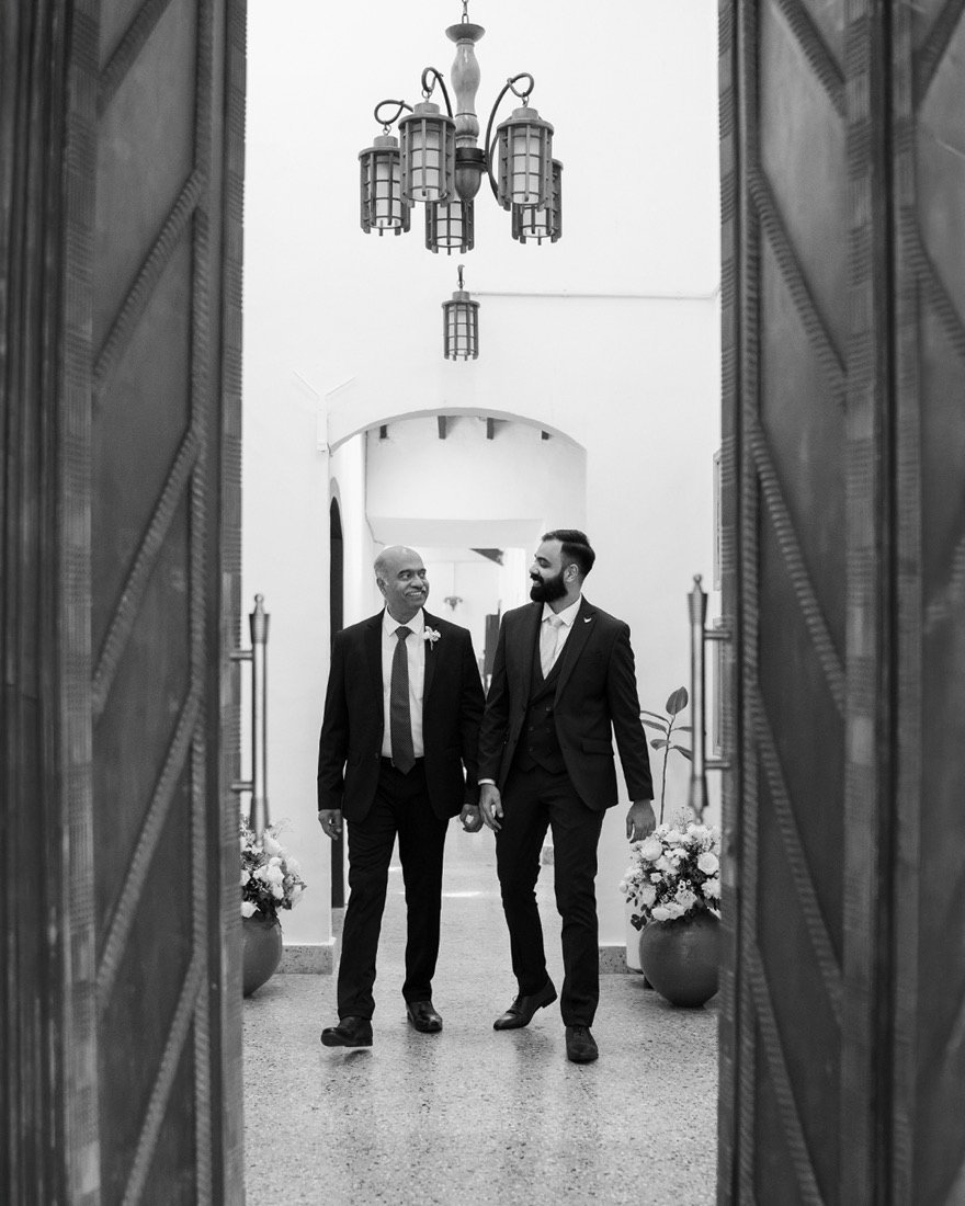 Two men in suits framed in a doorway, in black and white