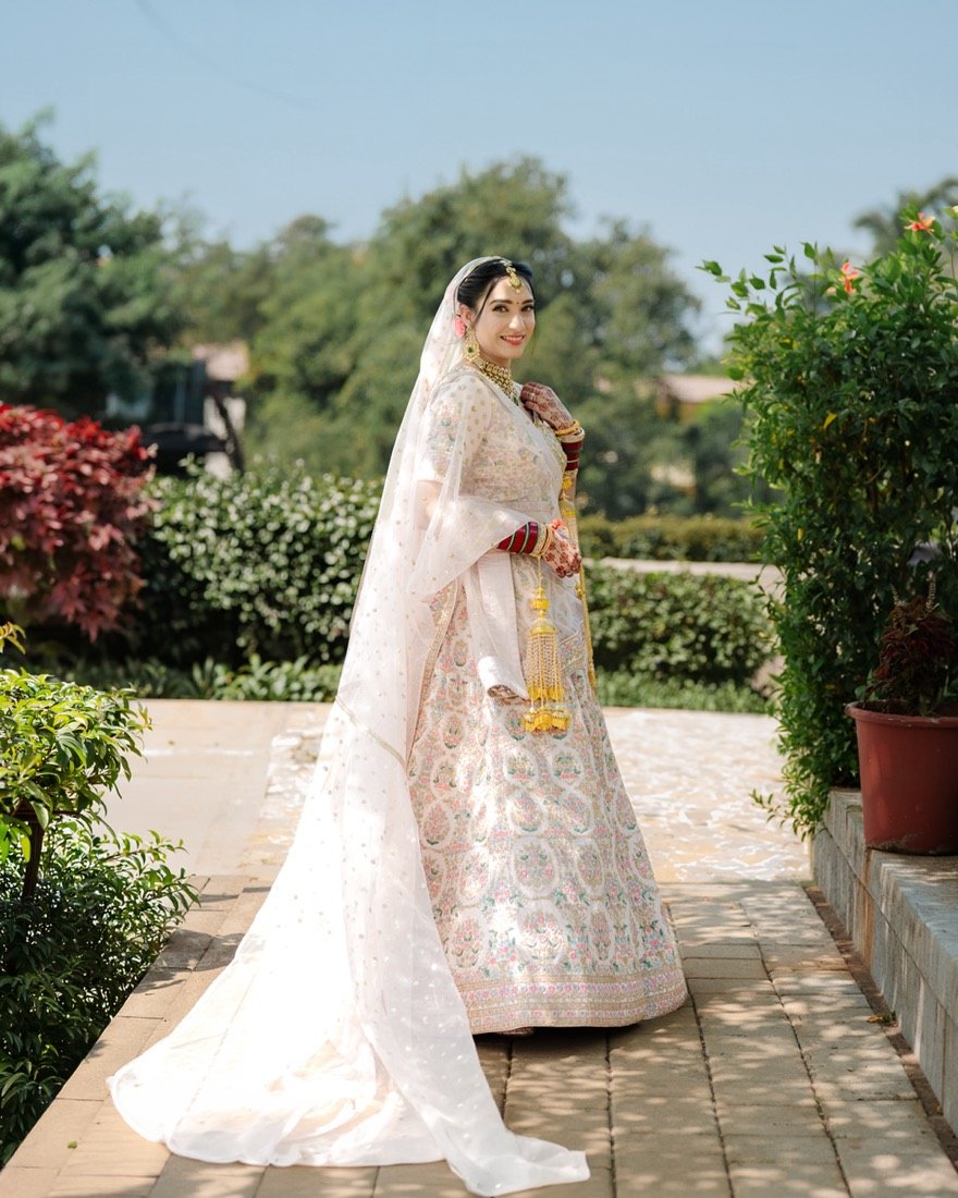 A bride in an ivory lehenga standing in a garden