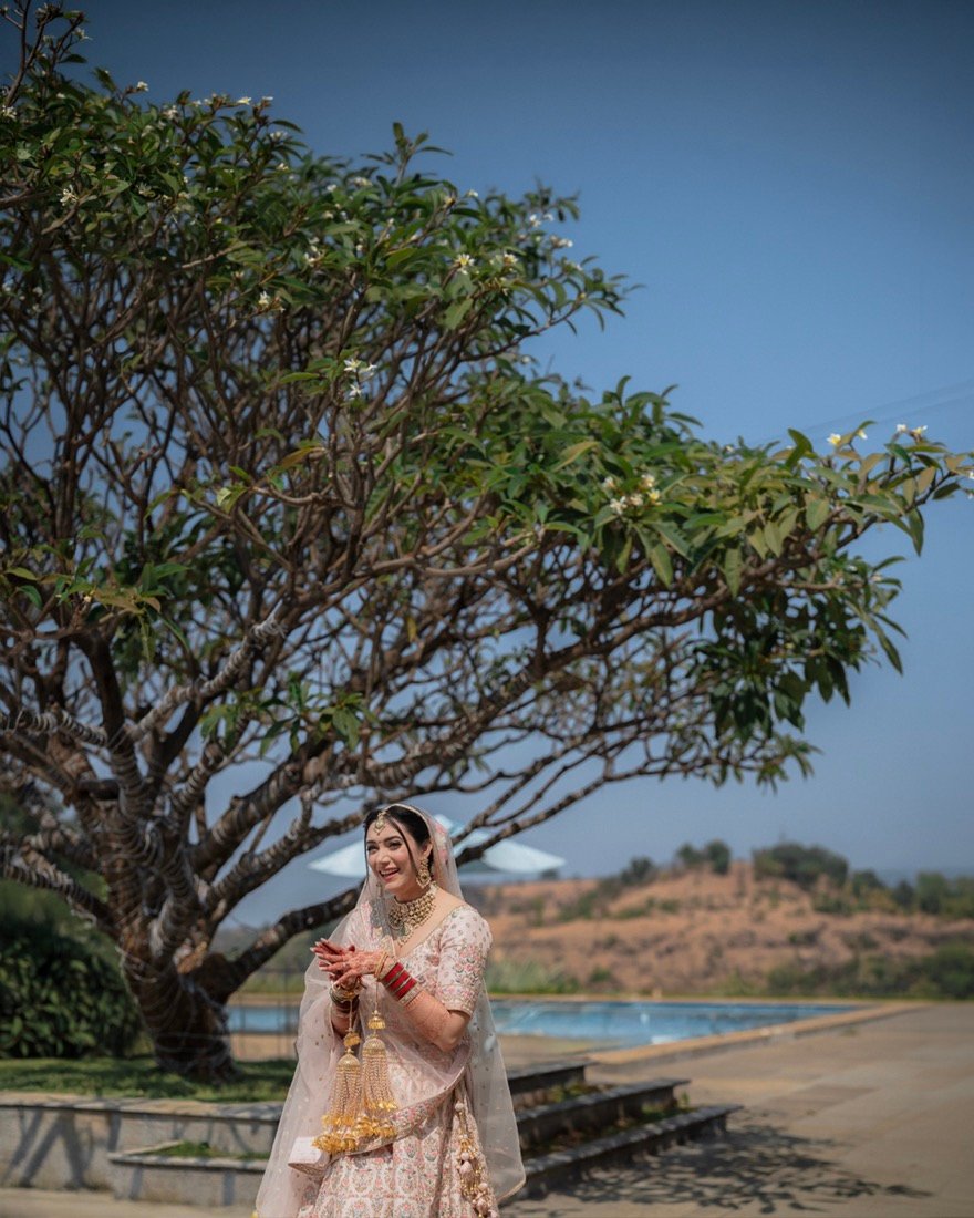 A bride beneath a frangipani tree beside a pool