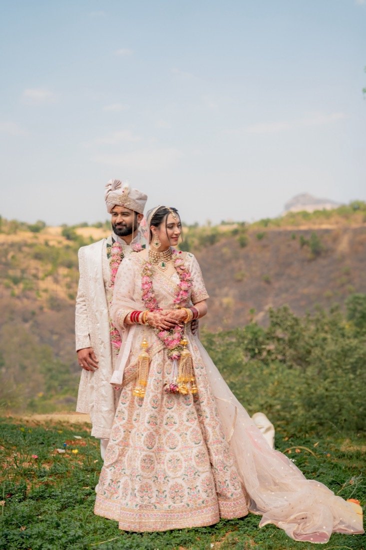 A bride and groom on a green hillside