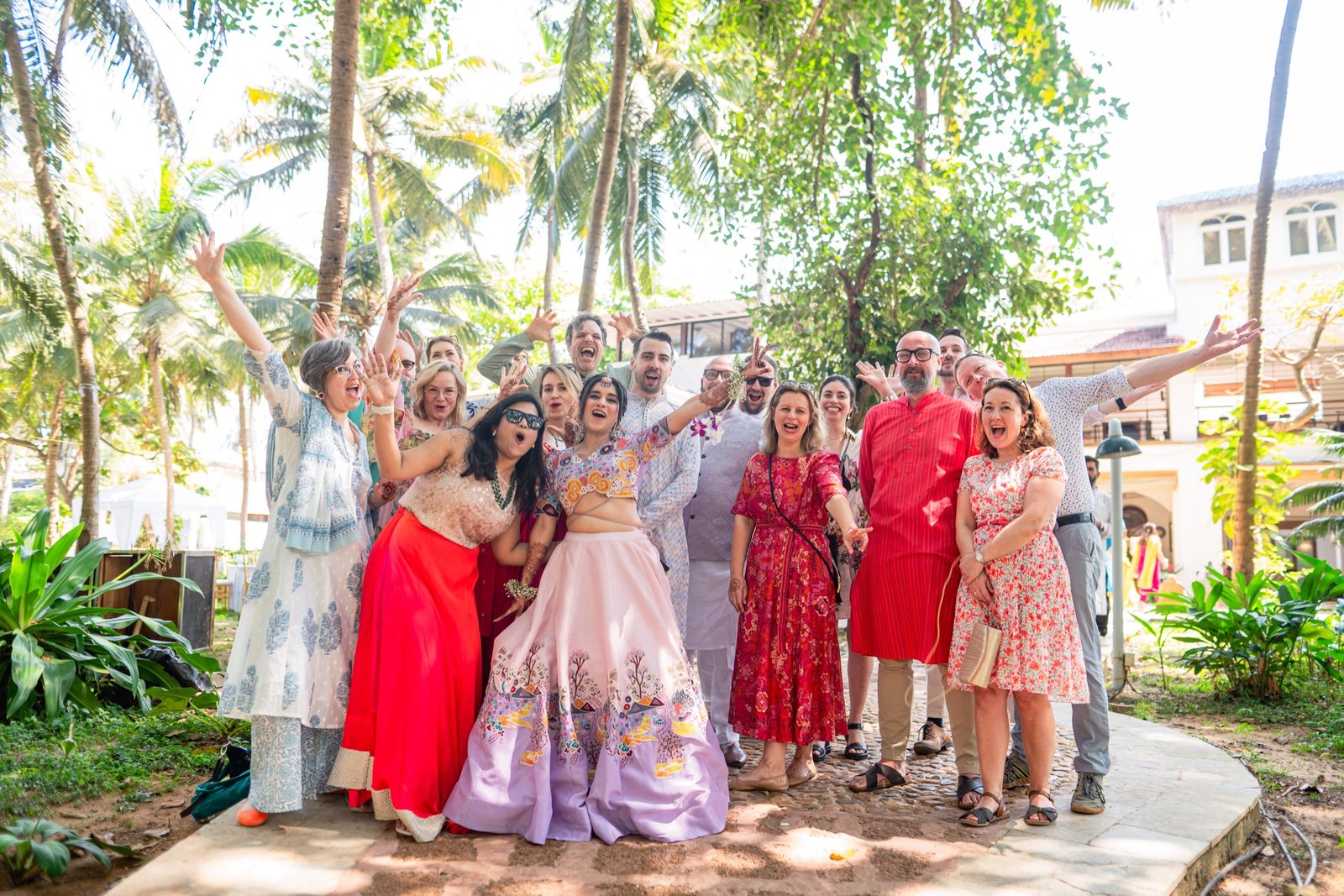 The wedding party and guests cheering together under the palms at a Goa wedding